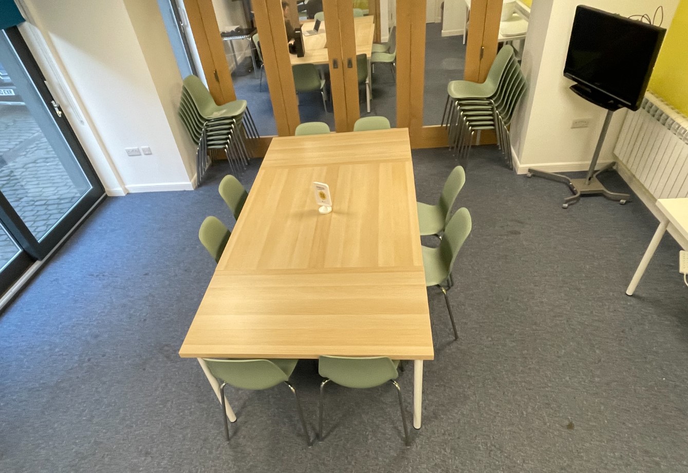 Photo of "The Studio" space from overhead, showing a tables, several chairs and a TV on a stand