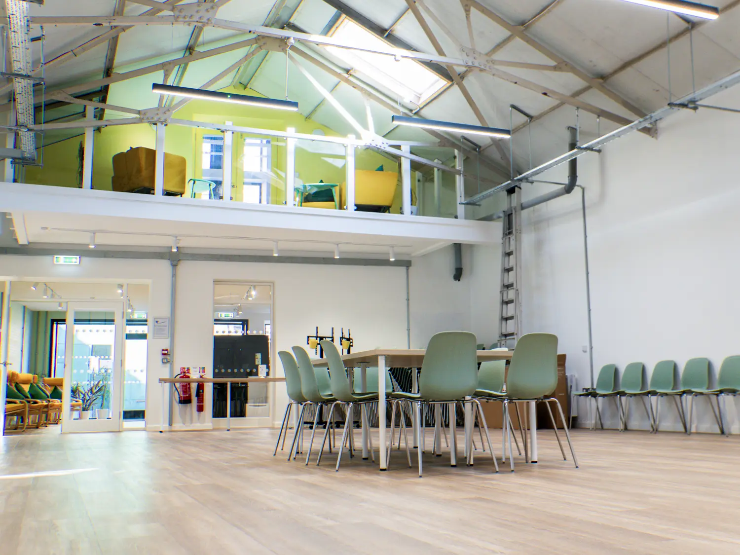 Photo showing a large, double height room with a balcony and wooden floor.