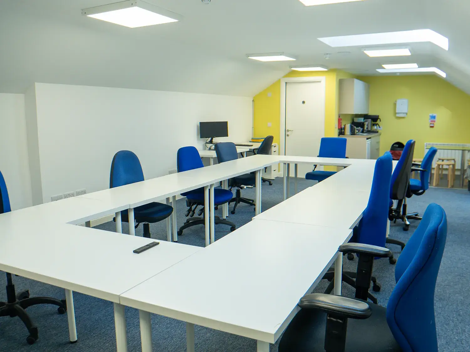 Photo of the "Design Room" space in Boardroom style with white table and blue office chairs.