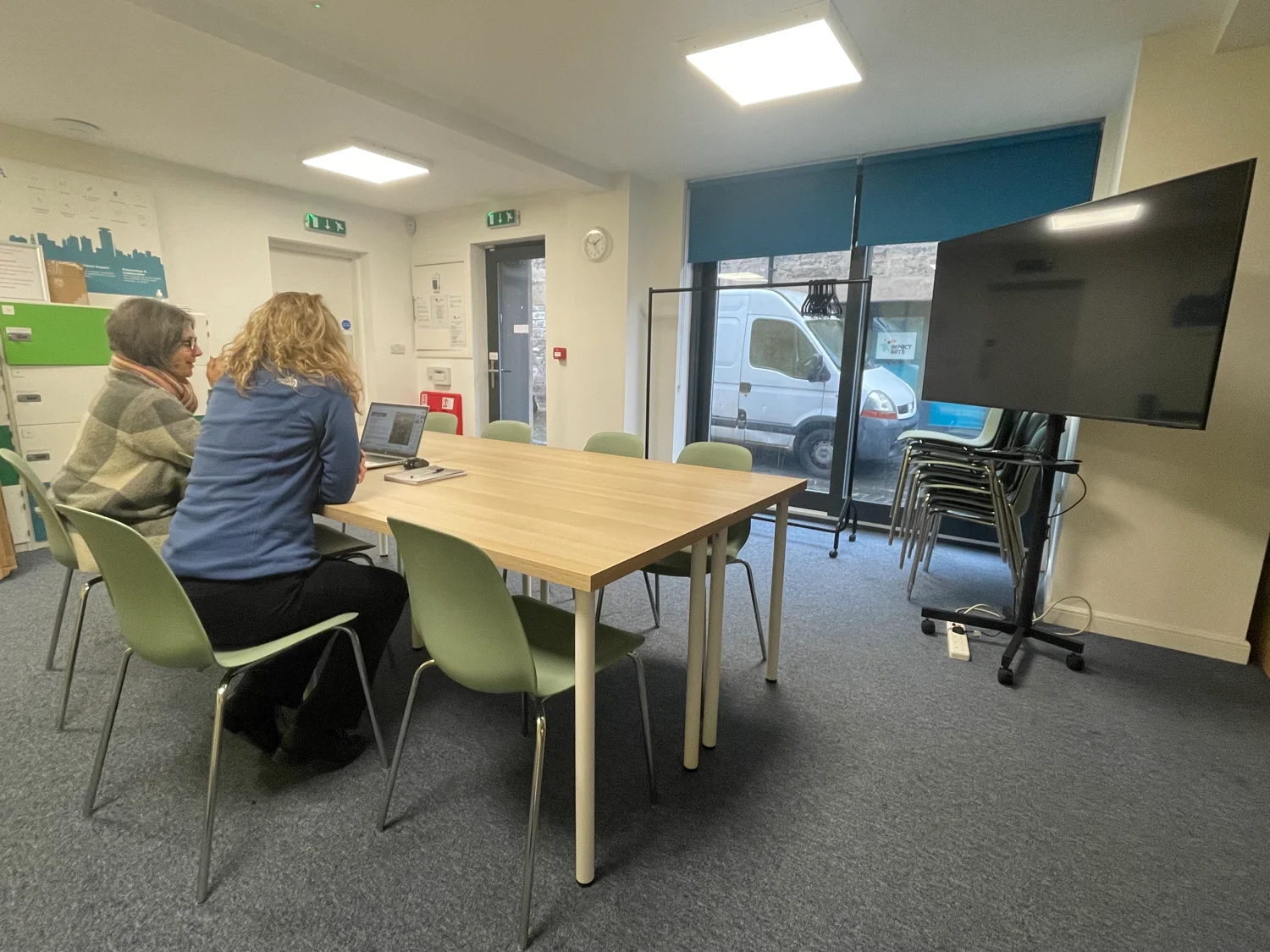 Photo of meeting room showing a meeting table and chairs, with a presentation screen.